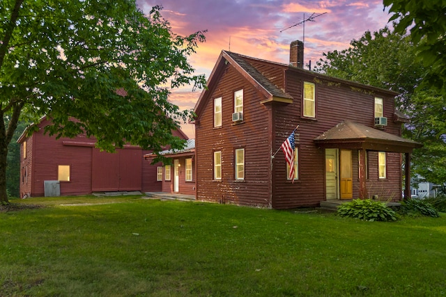 back house at dusk with a yard and cooling unit