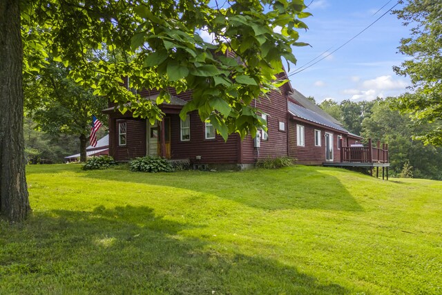 view of side of property featuring a deck and a lawn