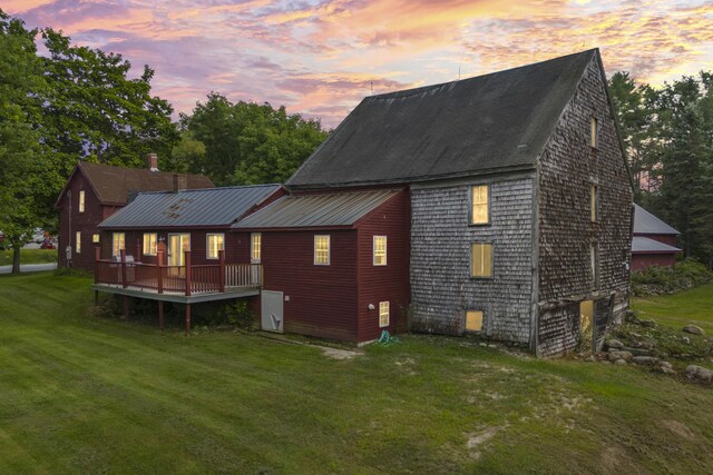 back house at dusk featuring a lawn