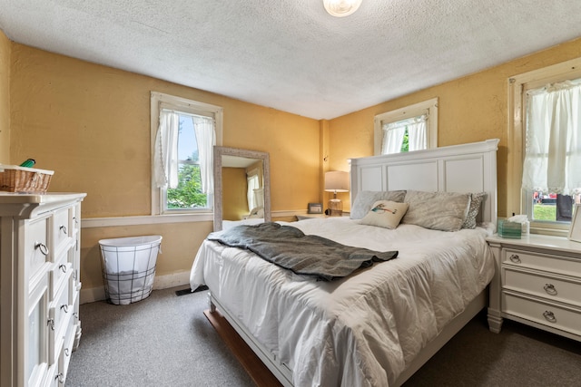 bedroom with a textured ceiling and dark carpet