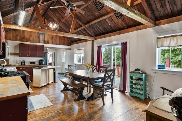 dining space with light hardwood / wood-style floors, beamed ceiling, high vaulted ceiling, ceiling fan, and wooden ceiling