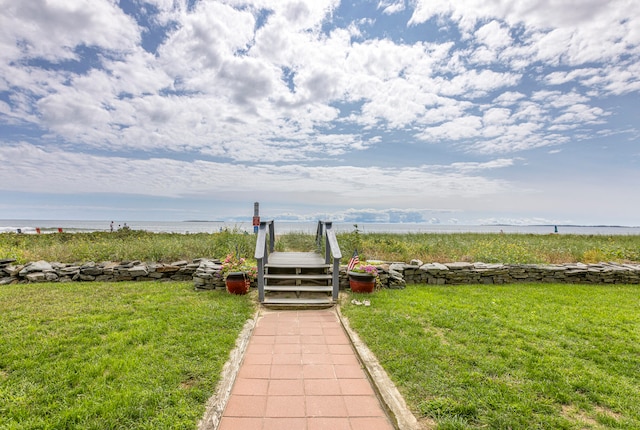 view of property's community with a water view and a lawn