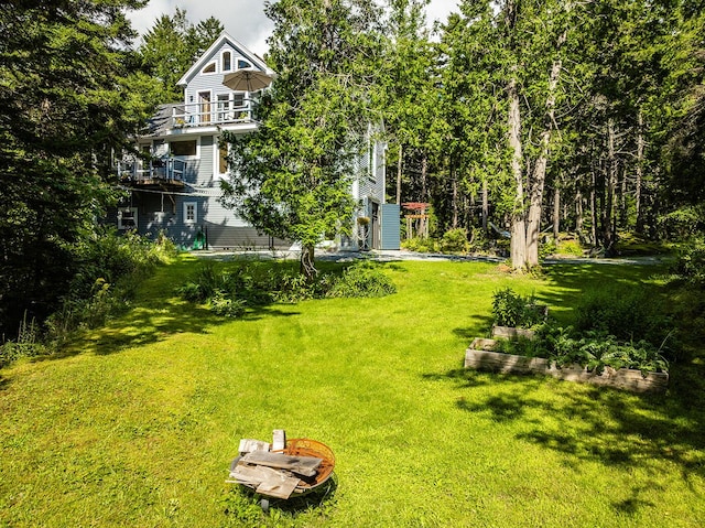 view of yard with a vegetable garden and a balcony