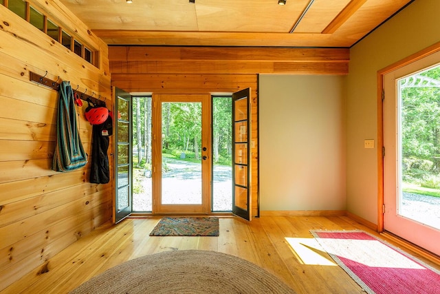 entryway with light wood-type flooring, wood walls, and baseboards