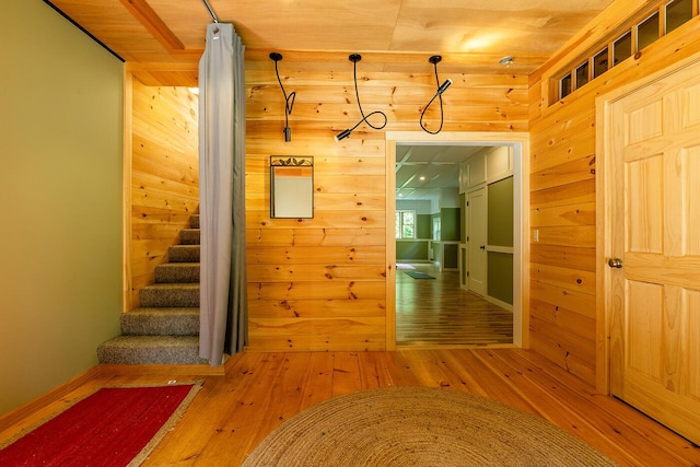 hallway with stairs, wood walls, and wood finished floors