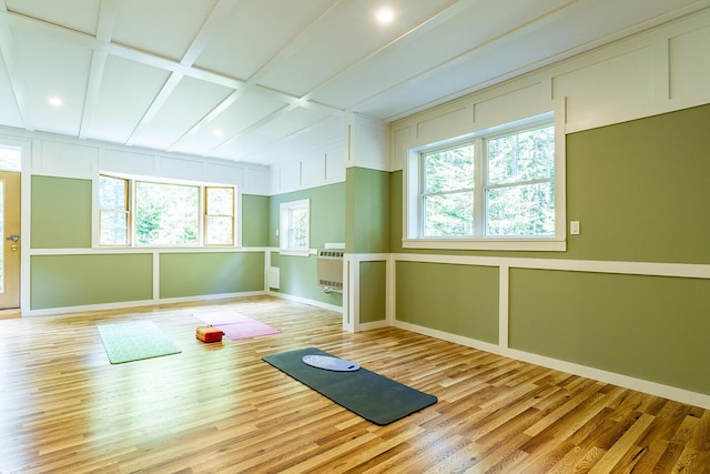 workout area with a healthy amount of sunlight, a decorative wall, and light wood finished floors