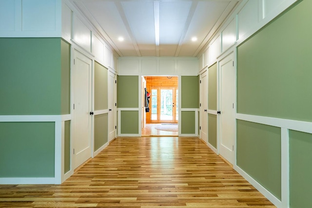 hallway featuring light wood-style floors and a decorative wall