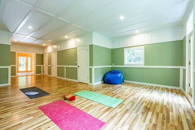 exercise area featuring french doors, coffered ceiling, baseboards, and light wood finished floors