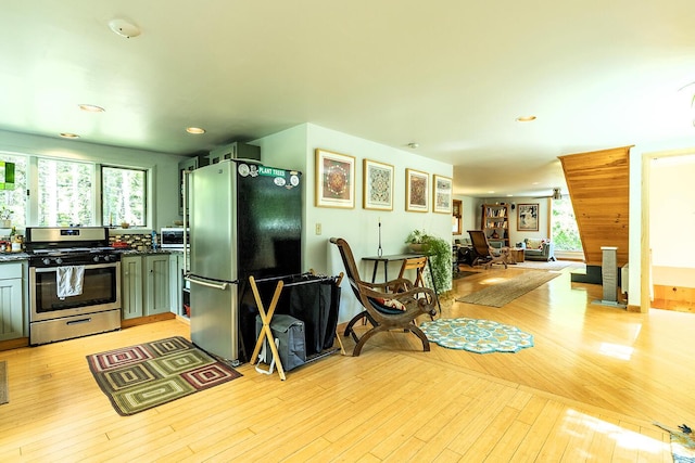 kitchen featuring appliances with stainless steel finishes, dark countertops, plenty of natural light, and light wood-style flooring