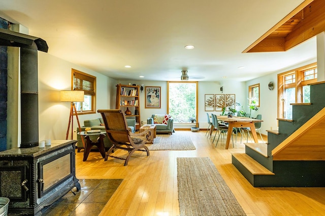 sitting room with recessed lighting, wood finished floors, a ceiling fan, stairway, and a wood stove