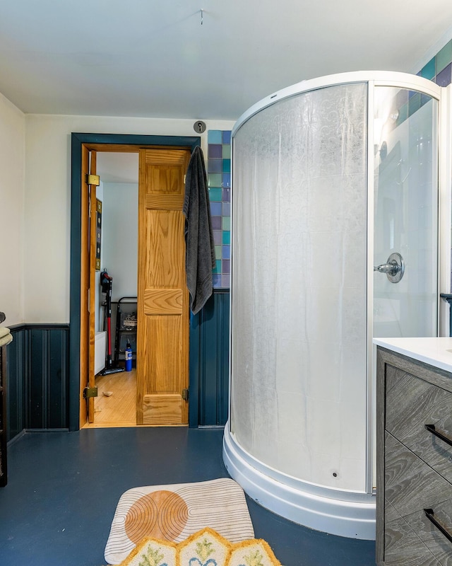 full bath featuring a stall shower and a wainscoted wall