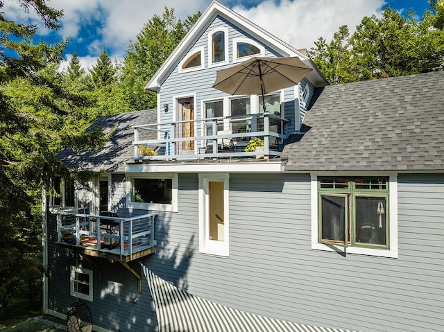 view of home's exterior featuring a balcony and roof with shingles