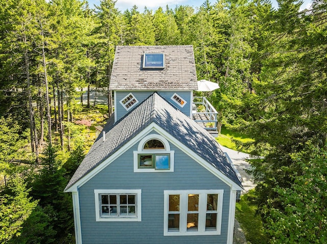 view of home's exterior featuring a high end roof and a forest view