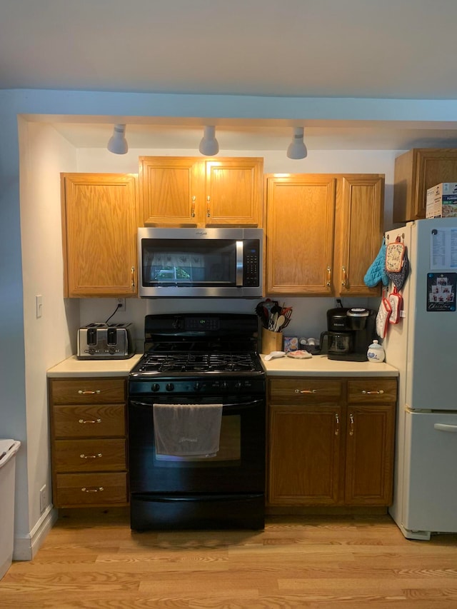 kitchen featuring light hardwood / wood-style floors, white refrigerator, and black range with gas cooktop