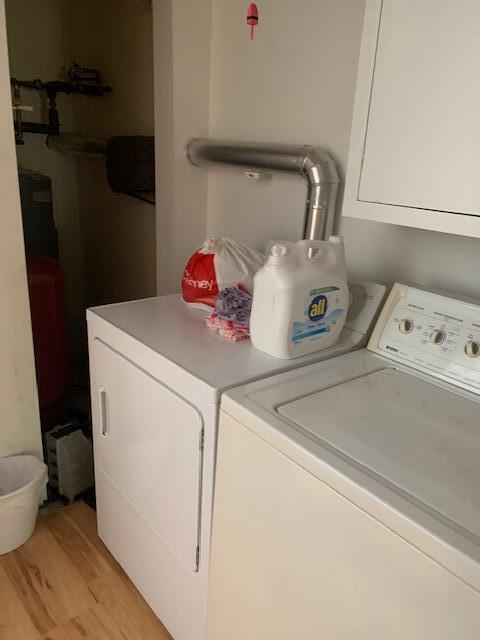 laundry area featuring light wood-type flooring, washer and dryer, and cabinets