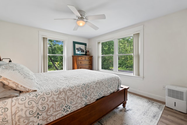 bedroom with ceiling fan, multiple windows, and hardwood / wood-style flooring