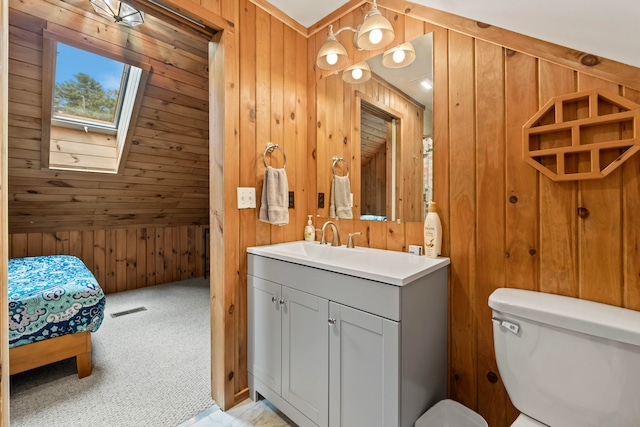 bathroom featuring vanity, toilet, a skylight, and wood walls