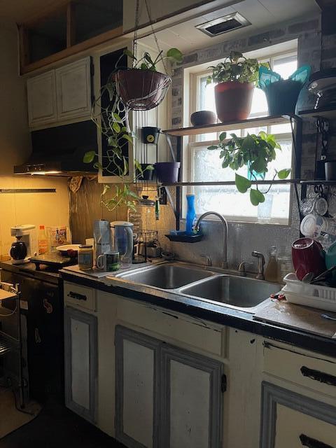 kitchen featuring dark countertops, a sink, visible vents, and white cabinetry