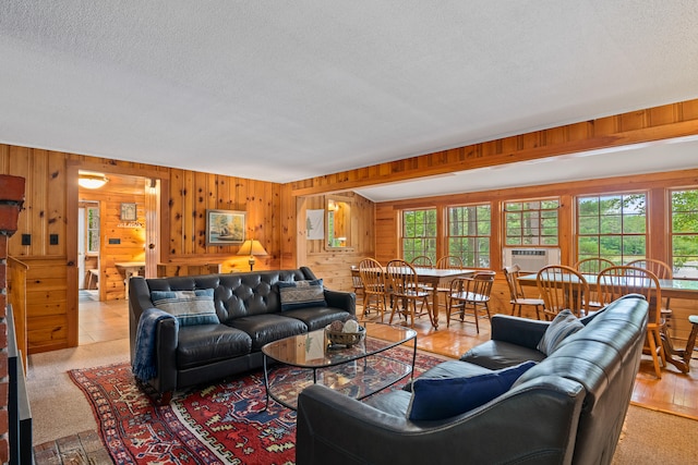 carpeted living room featuring a wealth of natural light, a textured ceiling, and wooden walls