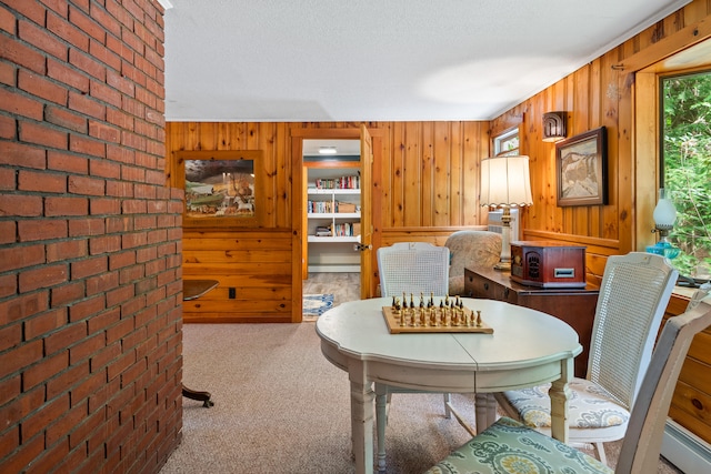 dining area featuring a textured ceiling, brick wall, wooden walls, and a baseboard heating unit