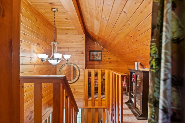 staircase with carpet, wood walls, wooden ceiling, a notable chandelier, and lofted ceiling