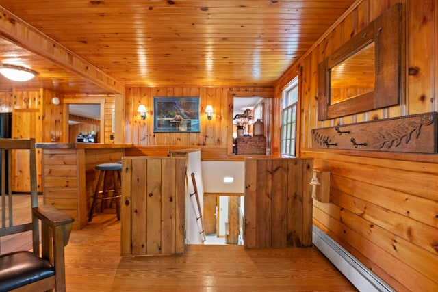 interior space featuring hardwood / wood-style floors, wood ceiling, baseboard heating, and wood walls