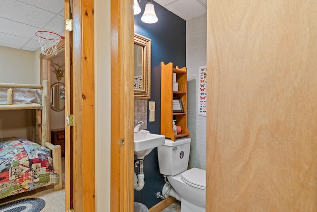 bathroom featuring tile patterned floors, toilet, and a drop ceiling