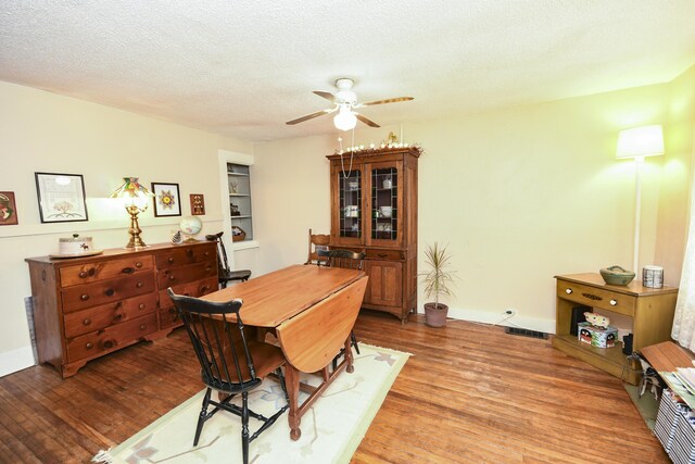 dining room with wood-type flooring, ceiling fan, and a textured ceiling