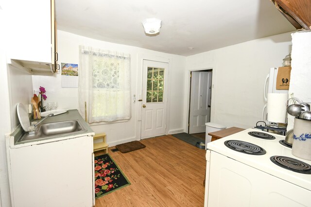 kitchen with white cabinets, sink, light hardwood / wood-style floors, and white appliances