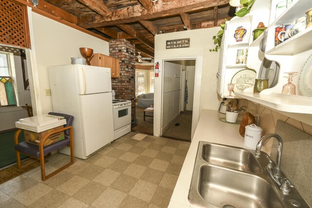 kitchen featuring white appliances, sink, and brick wall