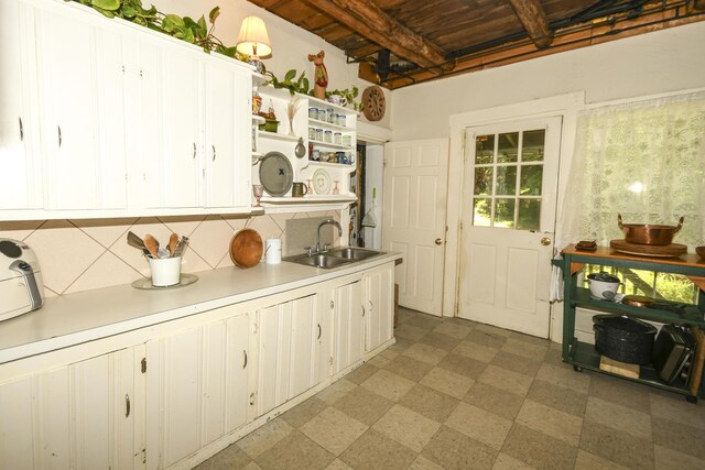 kitchen featuring white cabinetry, tasteful backsplash, wooden ceiling, beam ceiling, and sink