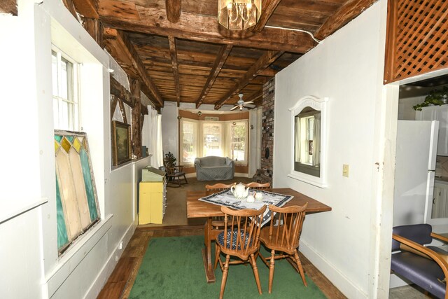 dining room with ceiling fan with notable chandelier, beam ceiling, dark hardwood / wood-style flooring, and wooden ceiling