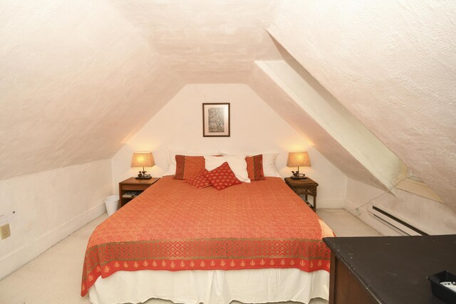 carpeted bedroom featuring a textured ceiling, lofted ceiling, and a baseboard heating unit