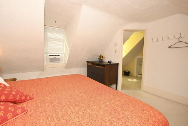 bedroom with cooling unit, a textured ceiling, and vaulted ceiling