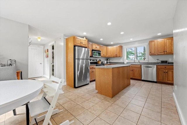 kitchen featuring light tile patterned floors, stainless steel appliances, sink, and a center island