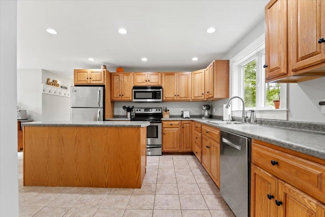 kitchen featuring light tile patterned floors, appliances with stainless steel finishes, sink, and a center island