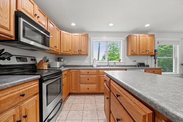 kitchen with light tile patterned floors, stainless steel appliances, sink, and a wealth of natural light