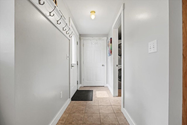 doorway featuring light tile patterned flooring and stacked washing maching and dryer