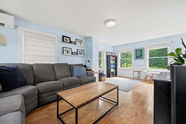 living room with an AC wall unit and light hardwood / wood-style floors