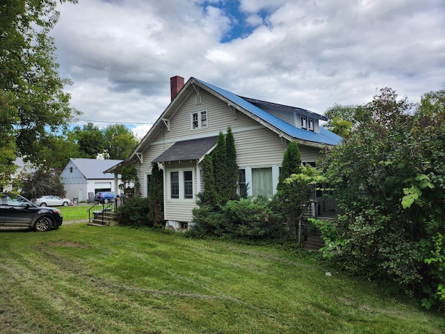 view of side of property with a chimney and a yard