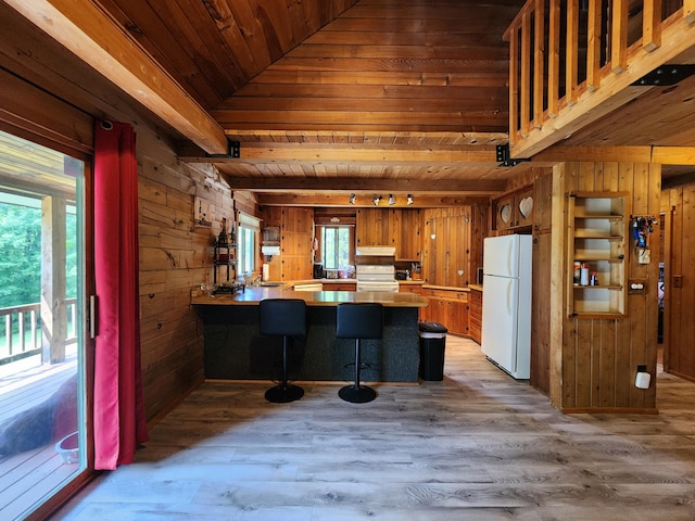 kitchen with kitchen peninsula, wood ceiling, wood walls, white appliances, and a breakfast bar area