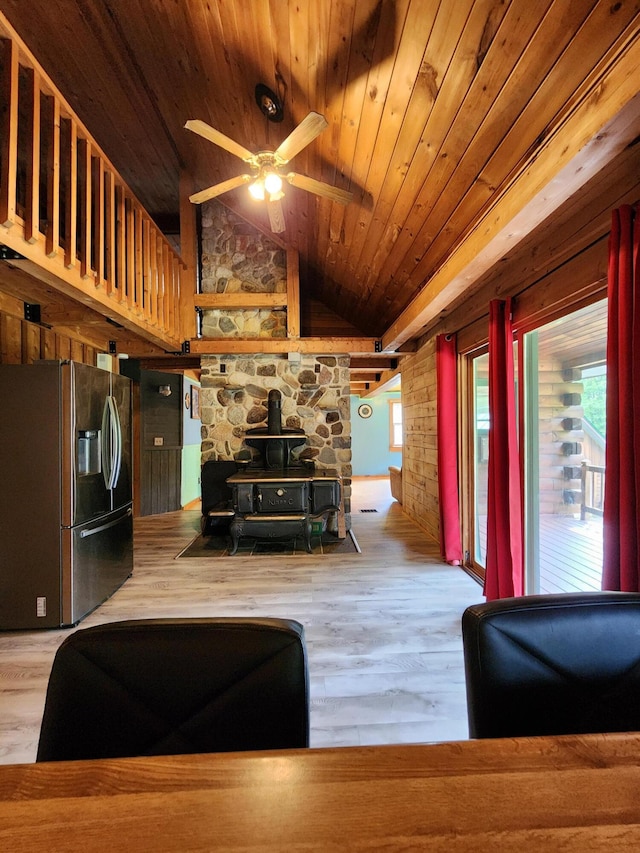 unfurnished living room with lofted ceiling, ceiling fan, light hardwood / wood-style floors, wood ceiling, and a wood stove