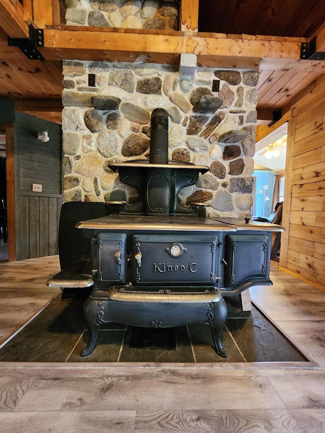 details featuring beamed ceiling, a wood stove, wood walls, and hardwood / wood-style floors