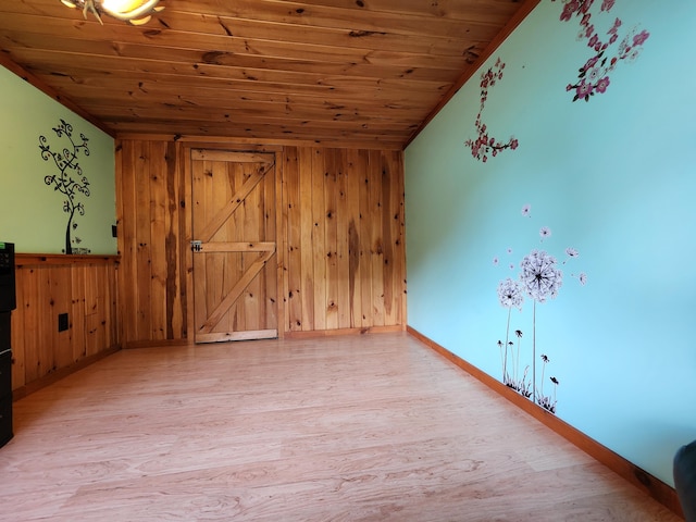 empty room featuring vaulted ceiling, hardwood / wood-style flooring, wood walls, and wood ceiling