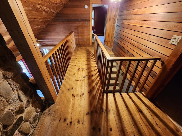 corridor with lofted ceiling, wooden ceiling, wood walls, and hardwood / wood-style floors