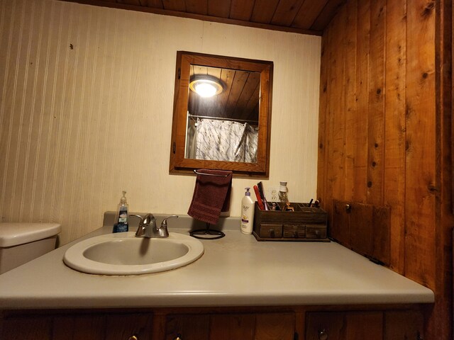 bathroom with wooden walls, sink, toilet, and wooden ceiling