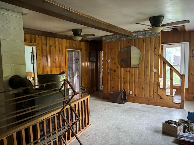 living room featuring wood walls, a ceiling fan, beamed ceiling, and tile patterned floors