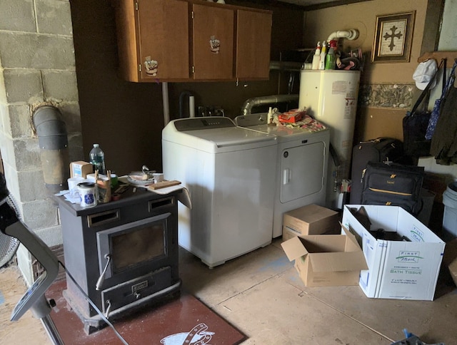 laundry area featuring concrete block wall, cabinet space, washing machine and clothes dryer, a wood stove, and gas water heater