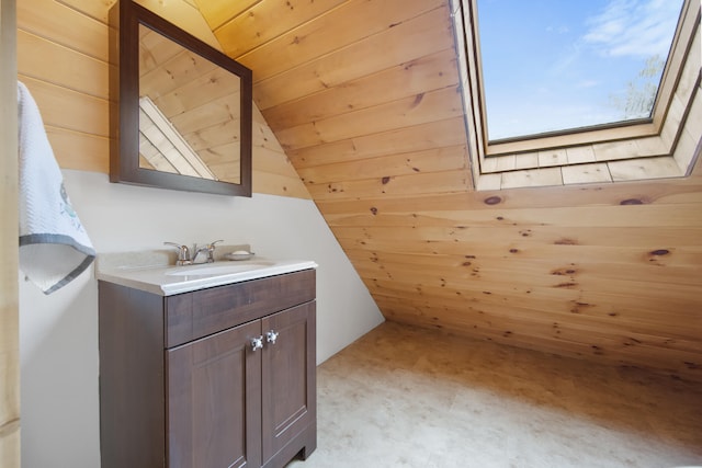 bathroom featuring vaulted ceiling with skylight, wooden walls, vanity, and a wealth of natural light