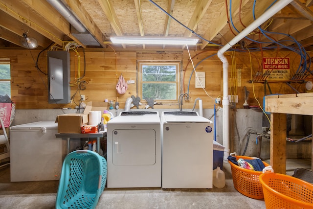 washroom featuring electric panel, wooden walls, and washer and clothes dryer